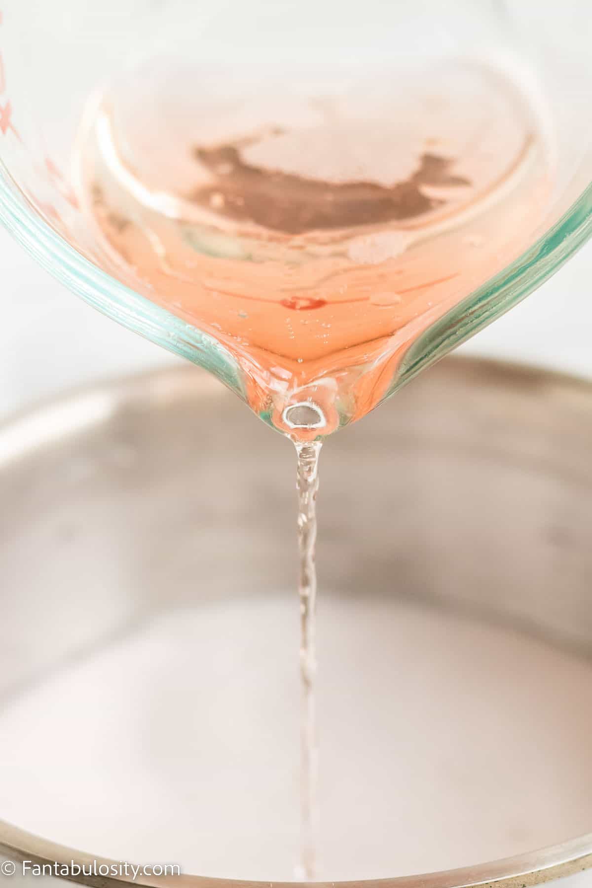 Pink champagne pouring in to mixing bowl.