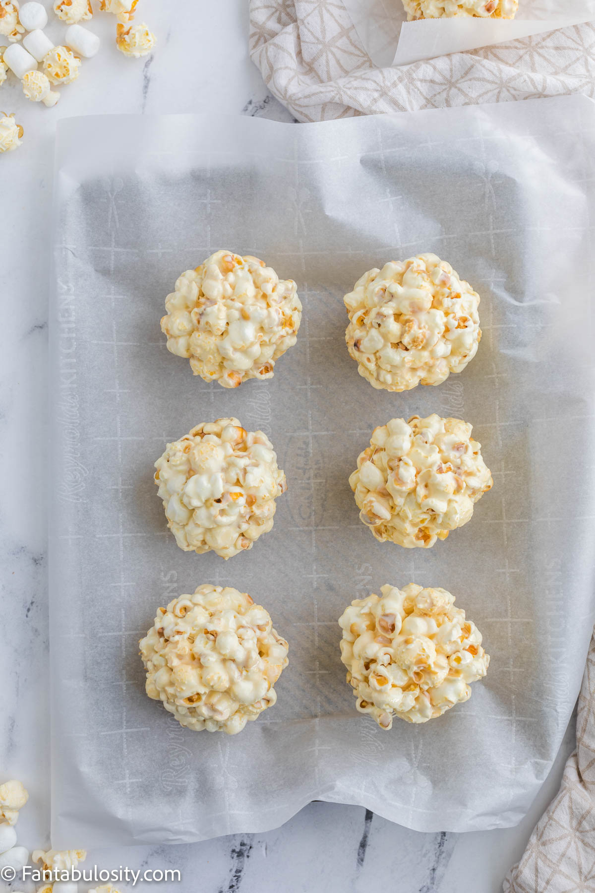 popcorn balls on parchment paper on baking sheet