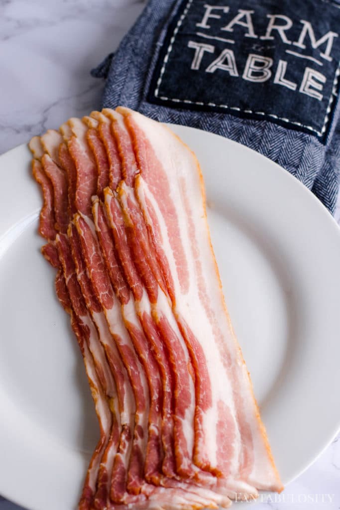 Raw uncooked thick bacon on a white plate