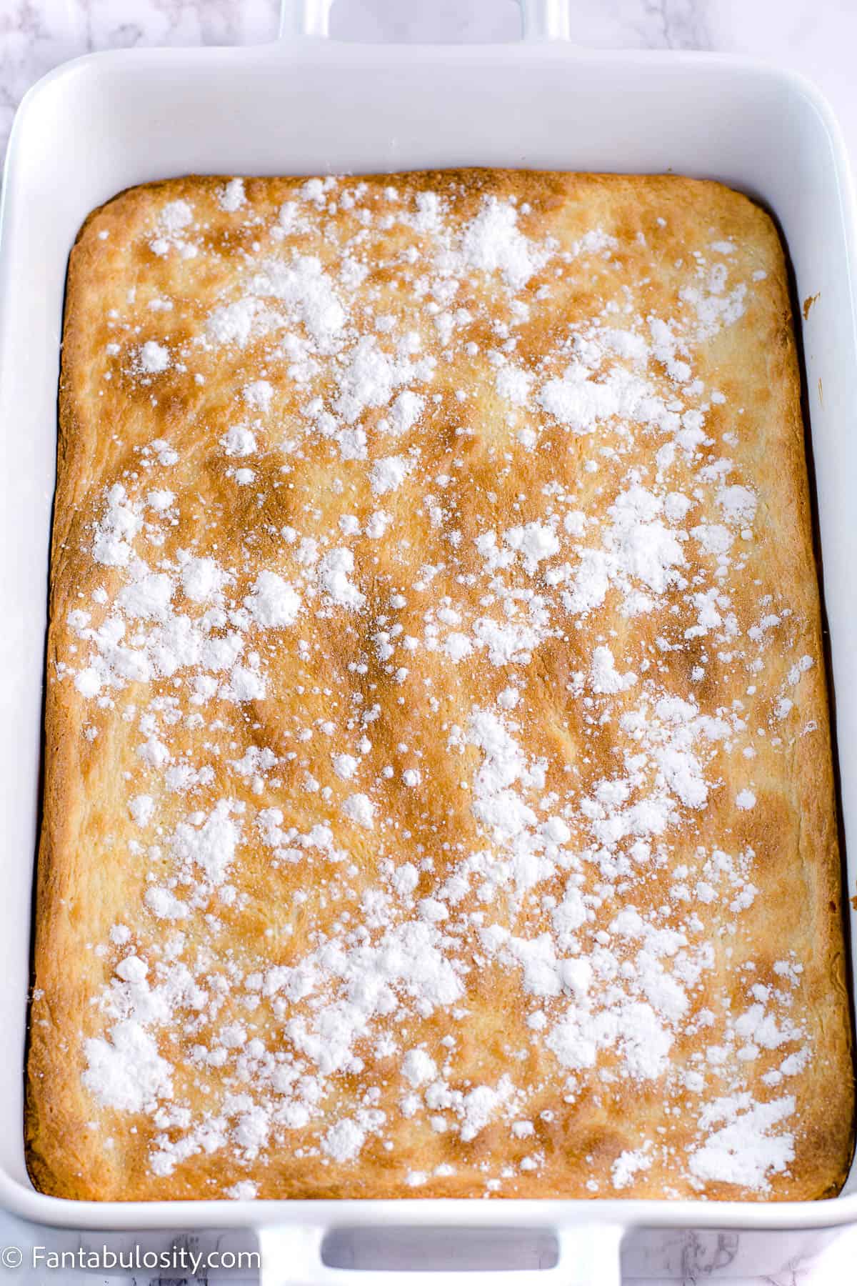 Powdered sugar sprinkled on top of gooey butter cake in white dish