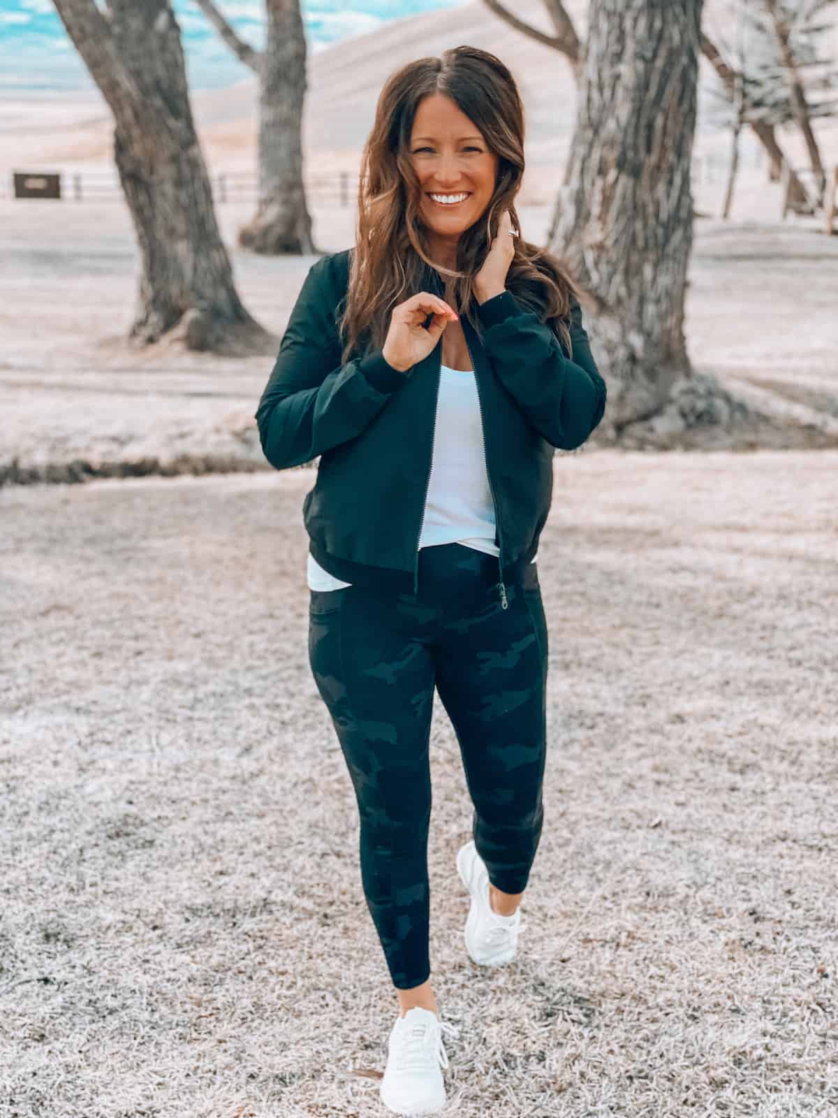 Woman posing in yoga pants and a black jacket