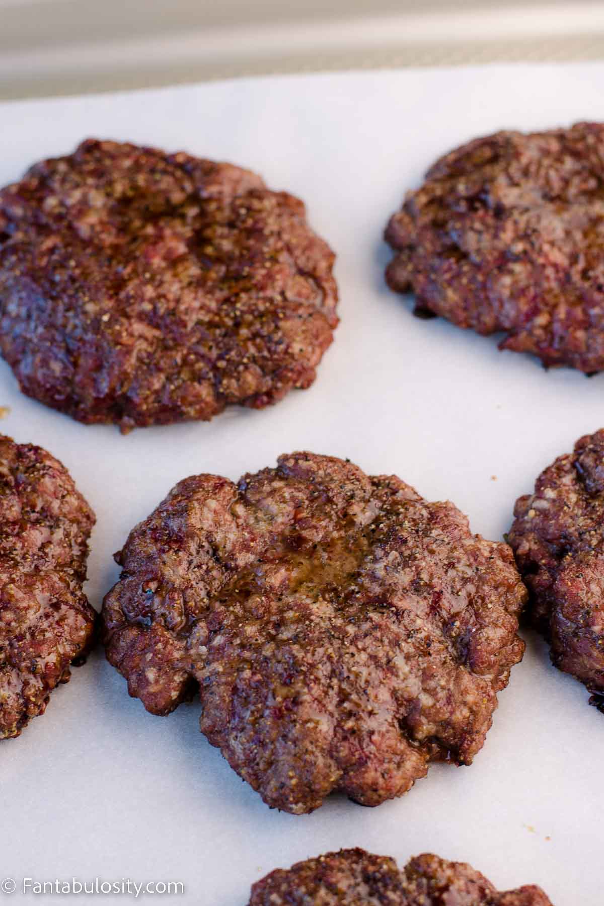 Cooked smoked burgers on parchment paper, showing how the juices are trapped.