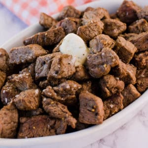 steak bites in white dish with butter on top