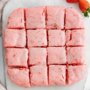 Strawberry brownies on white marble cutting board.