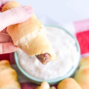 Hand holding breakfast pigs in a blanket
