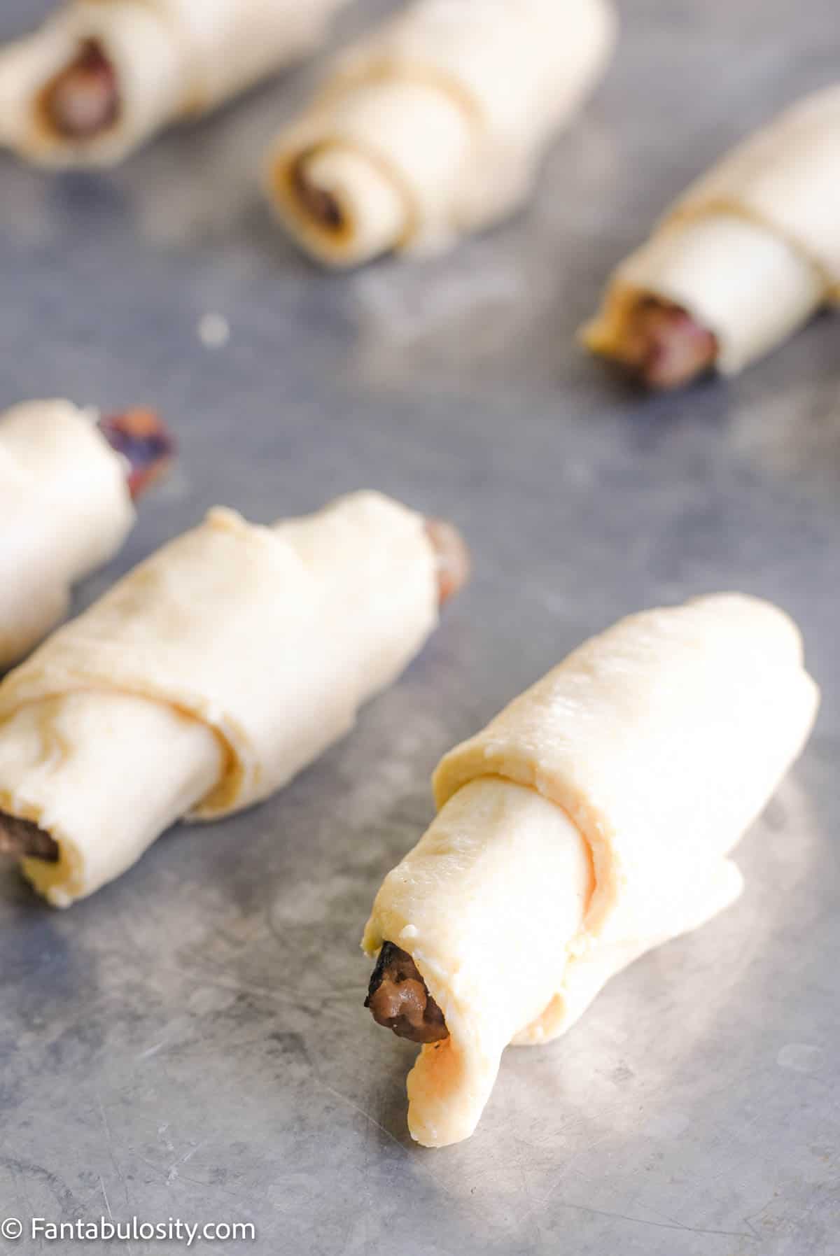 sausage links inside of crescent rolls on cookie sheet