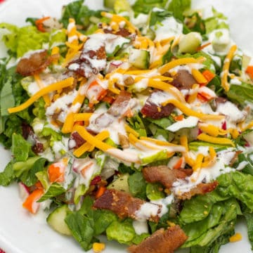 side salad on white plate drizzled with ranch