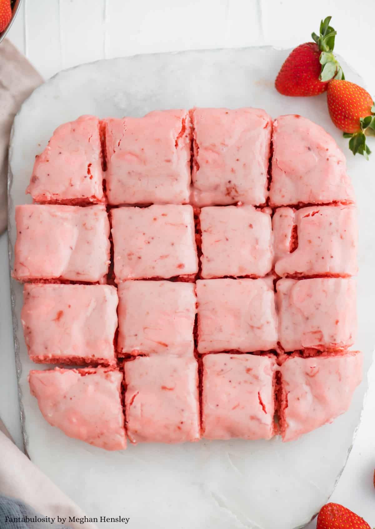 Strawberry brownies, baked on white marble cutting board, sliced in to squares.