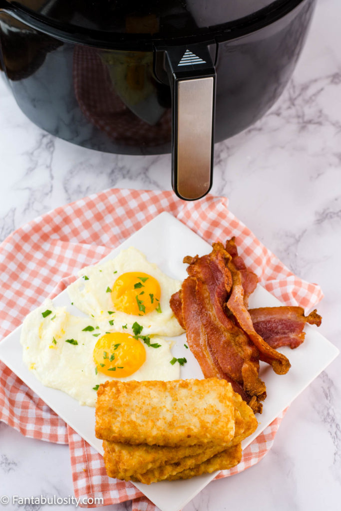 hash brown patties, eggs and bacon on plate next to air fryer
