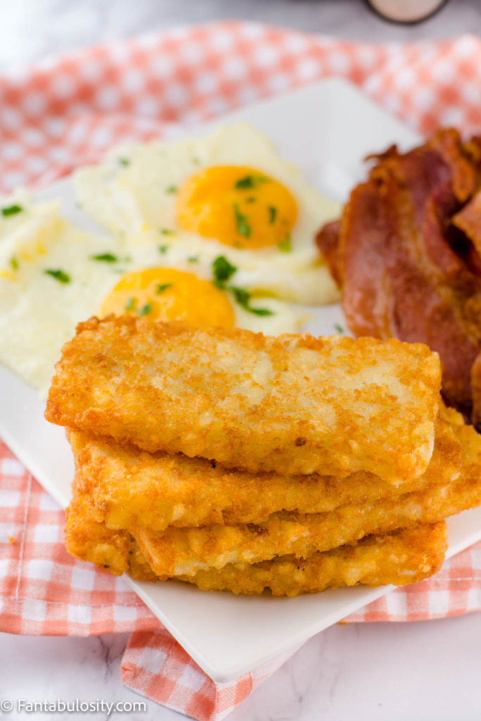 A plate with hash browns, eggs and bacon.