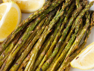 air fryer asparagus on a white plate with lemon wedges