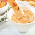 Chipotle Aioli in small bowl, with a polenta fry dipping in to it.