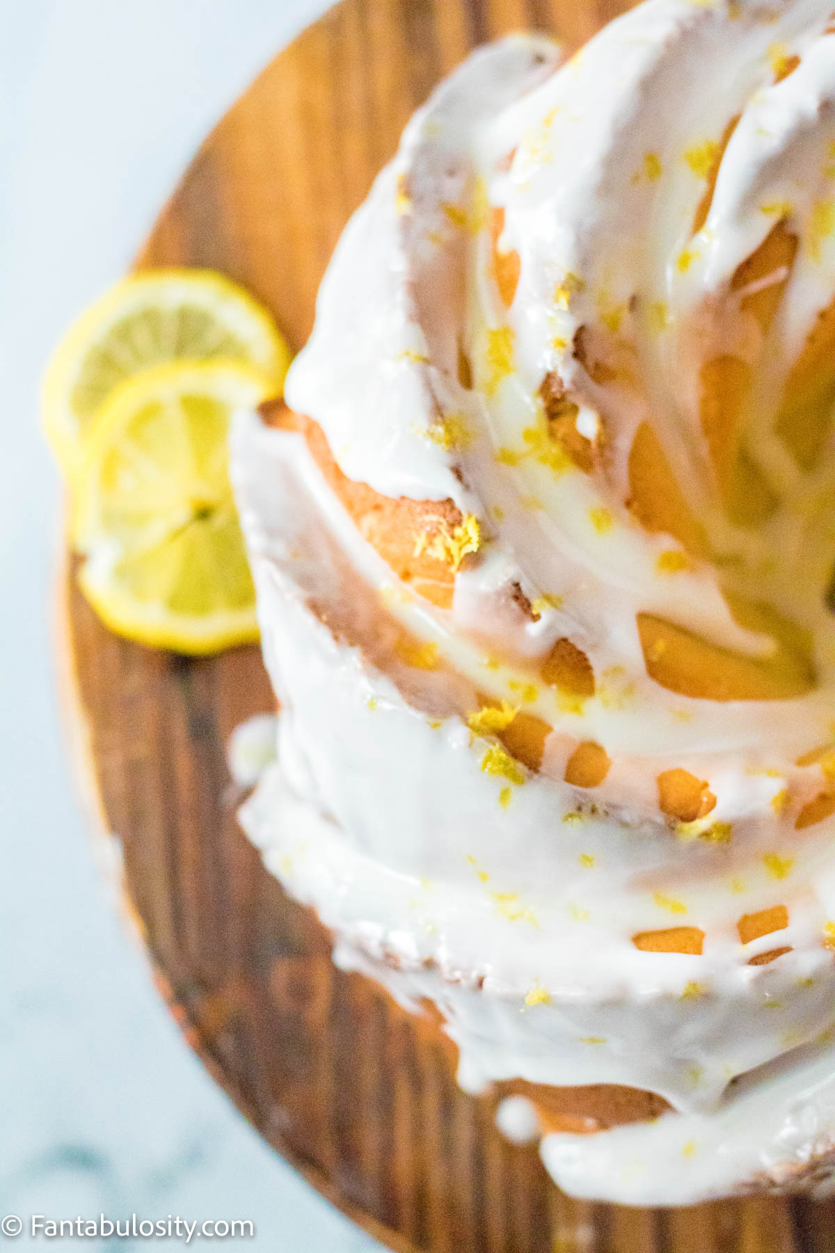 Lemon bundt cake sitting on wooden cake stand.