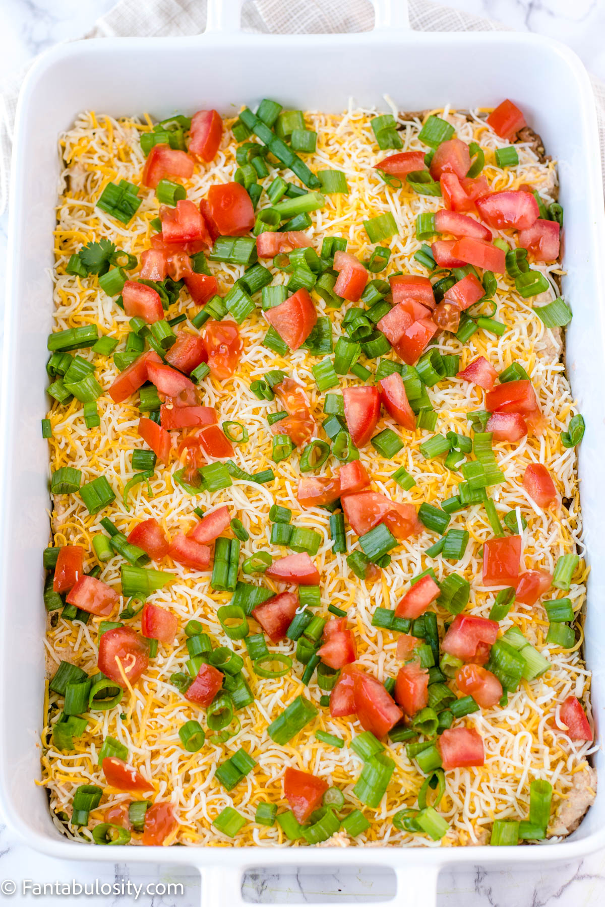 diced tomatoes on top of 7 layer dip