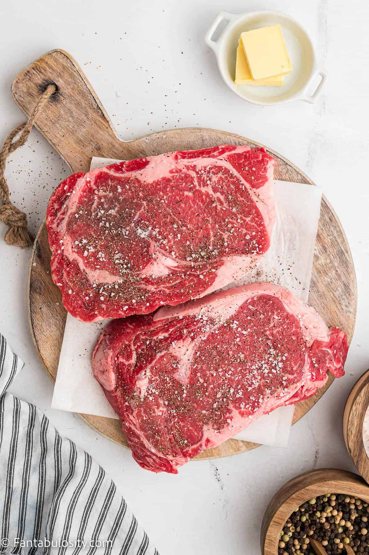 Ribeye Steaks on cutting board with salt and pepper sprinkled on them