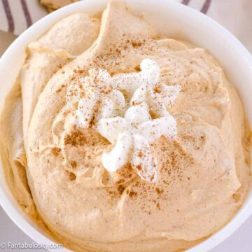 Pumpkin fluff in Pyrex serving bowl, with Reddi Wip and pumpkin pie spice on top.