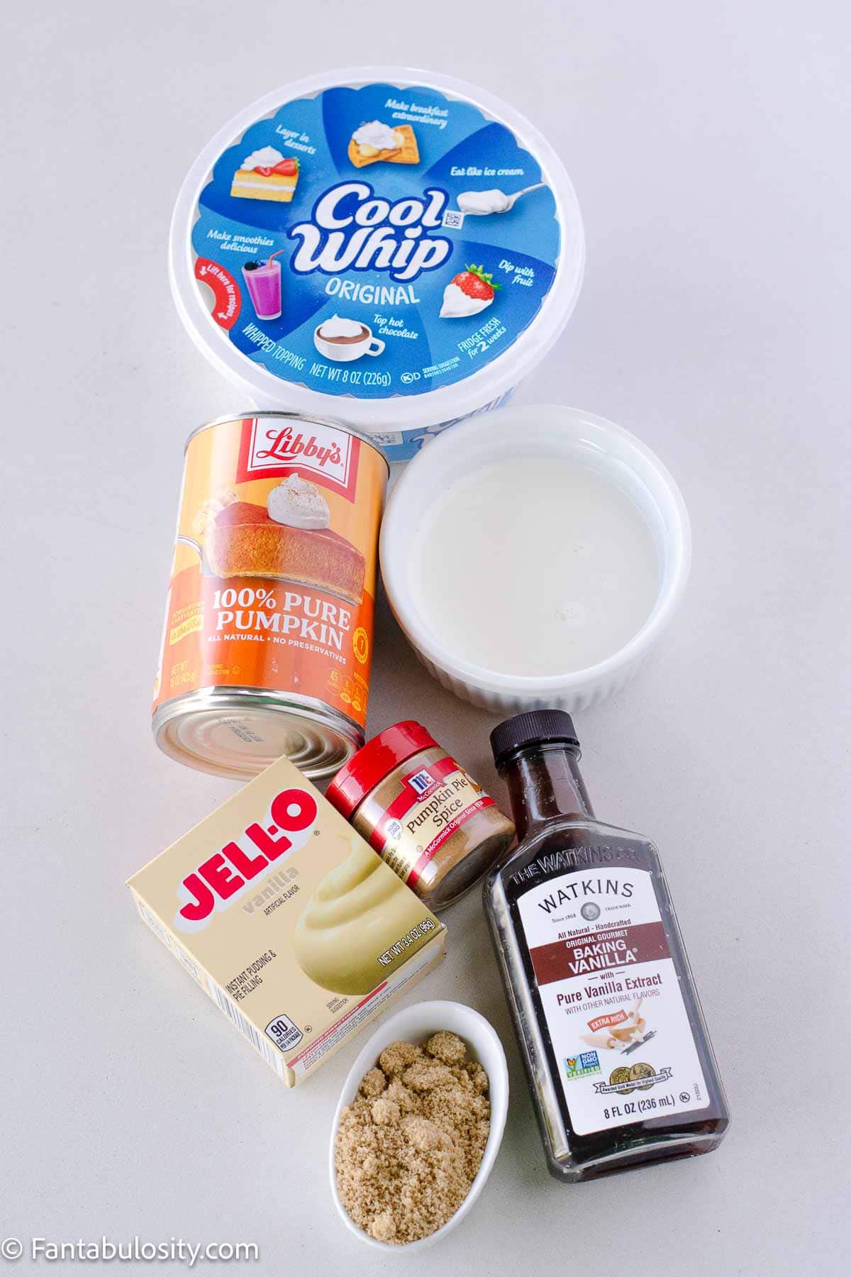 Cool Whip, pumpkin, half and half, pumpkin pie spice, brown sugar, vanilla pudding and vanilla on table.