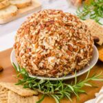 Cheeseball covered in nuts on platter.