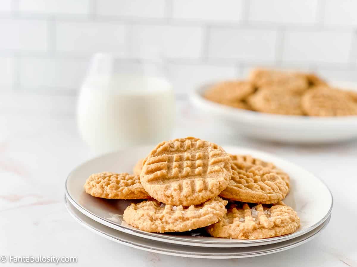 A plate of easy peanut butter cookies with a glass of milk in the background.
