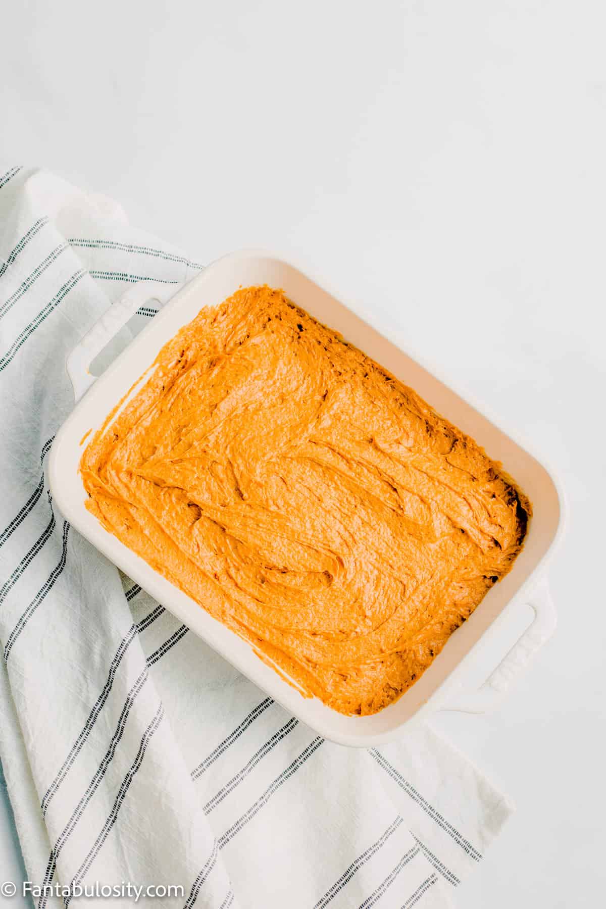 Baking dish filled with pumpkin cake batter