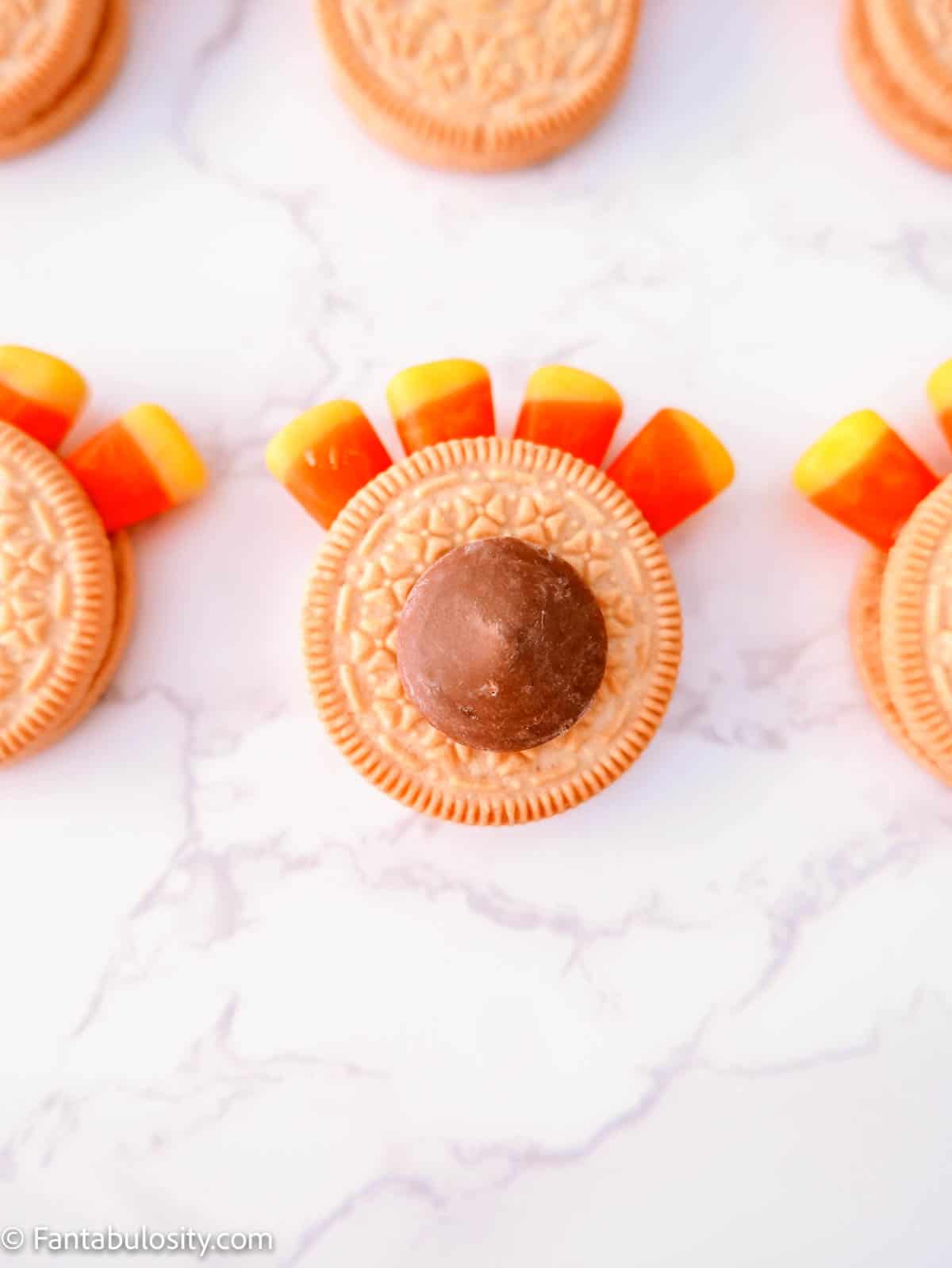 A golden Oreo with candy corn feathers and a candy melt on top.