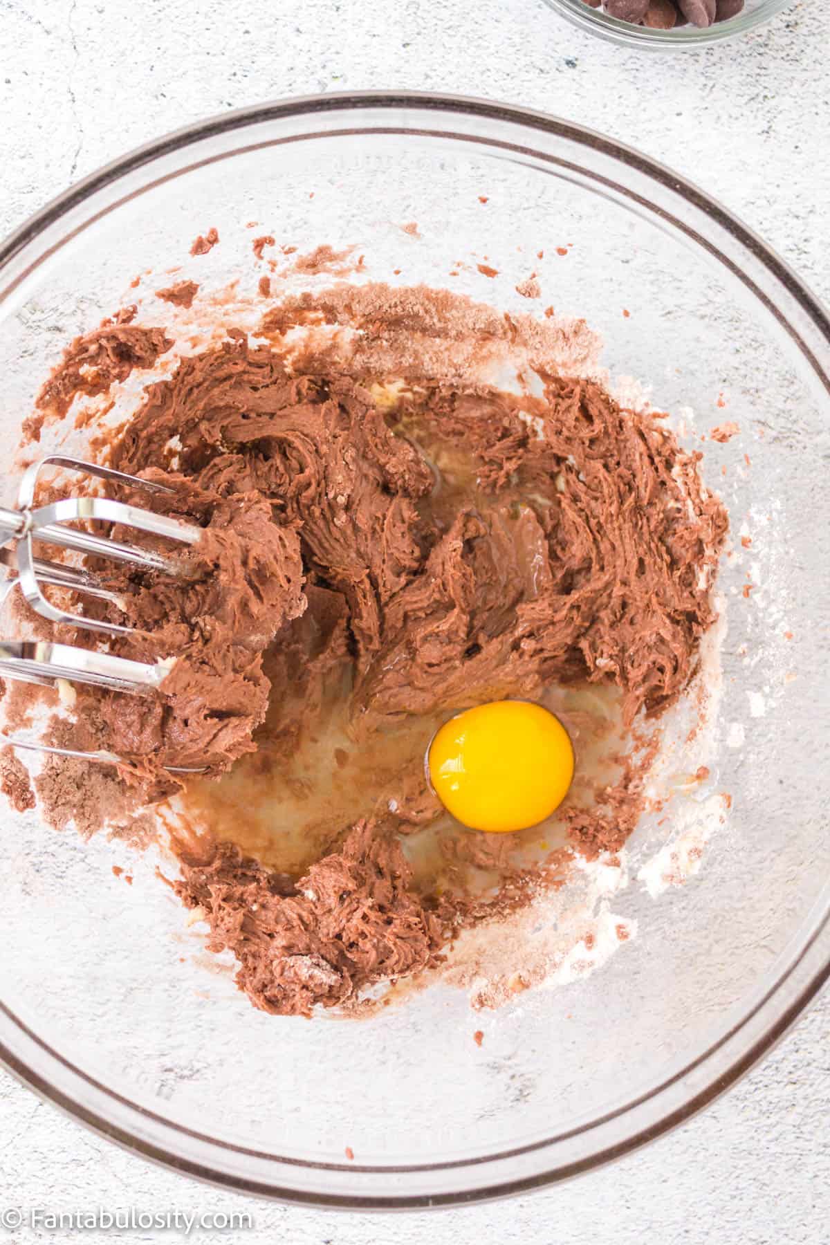 Brownie mix with egg, milk and other ingredients in glass bowl.