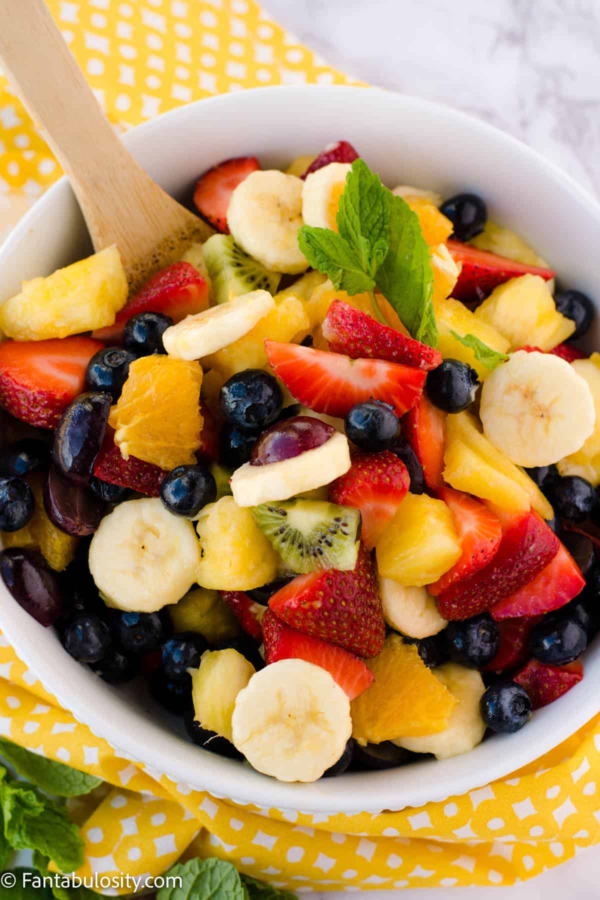 Honey lime fruit salad in white bowl.