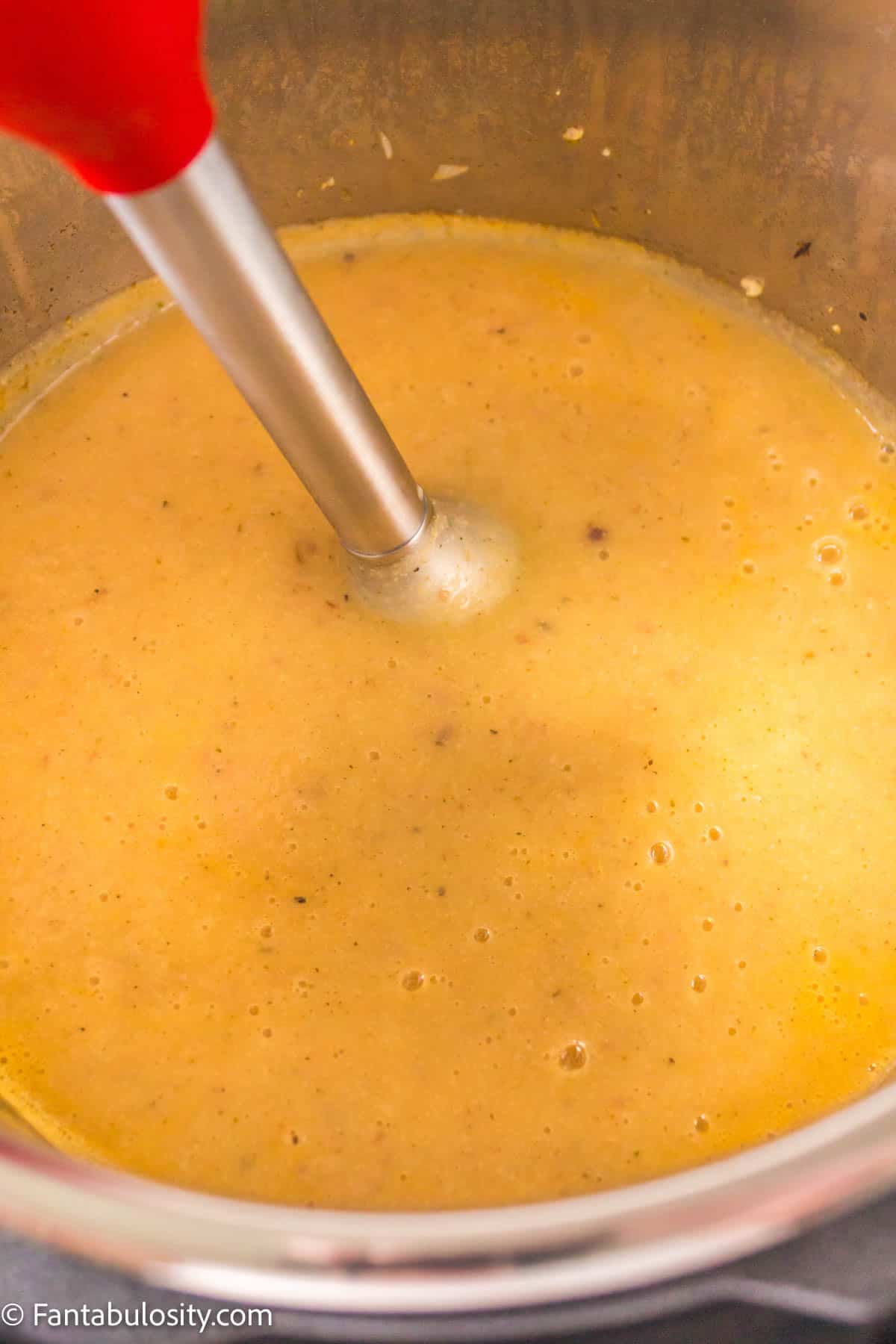 Use immersion blender to blend instant pot cauliflower soup smooth.
