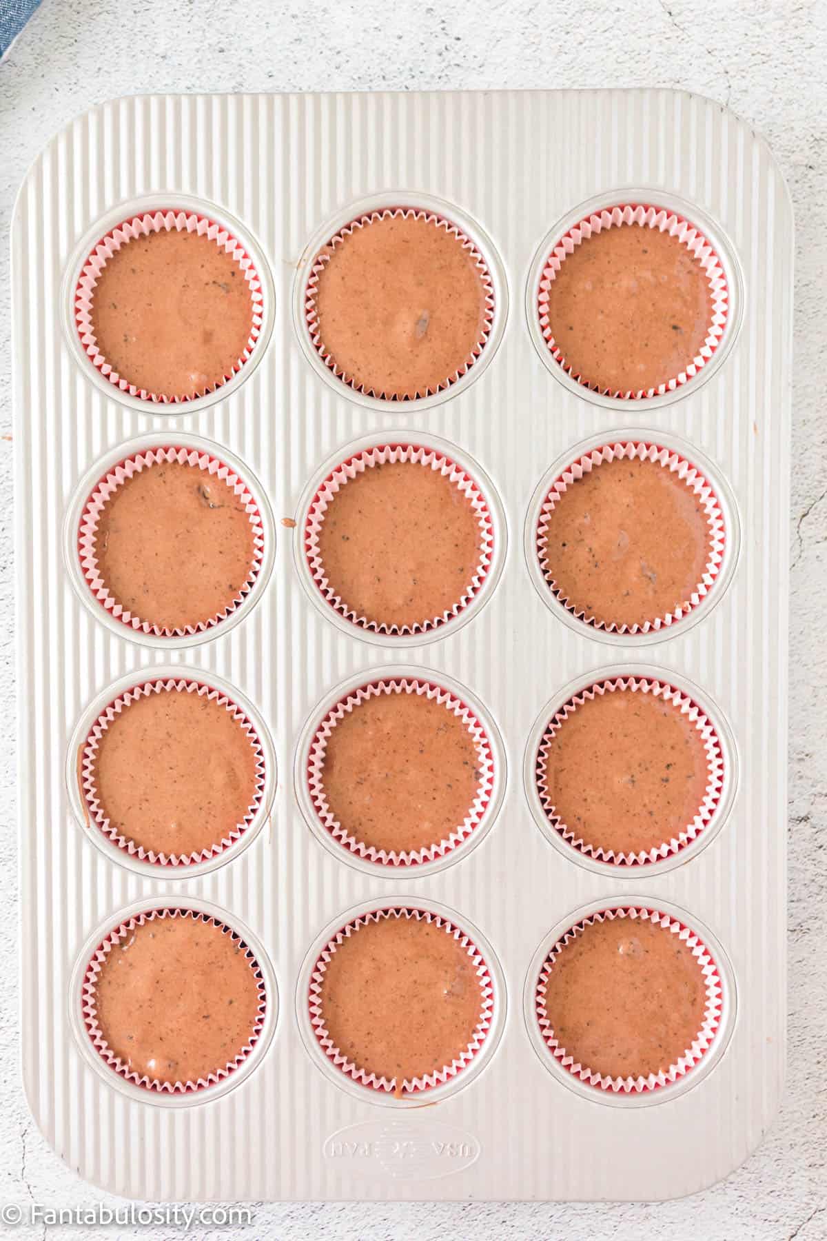 Oreo cupcake batter in muffin tin.
