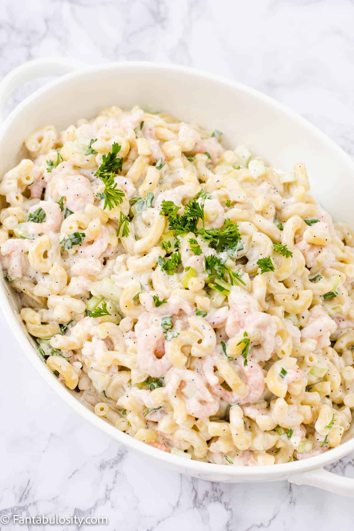 
A large white bowl filled with shrimp pasta salad.
