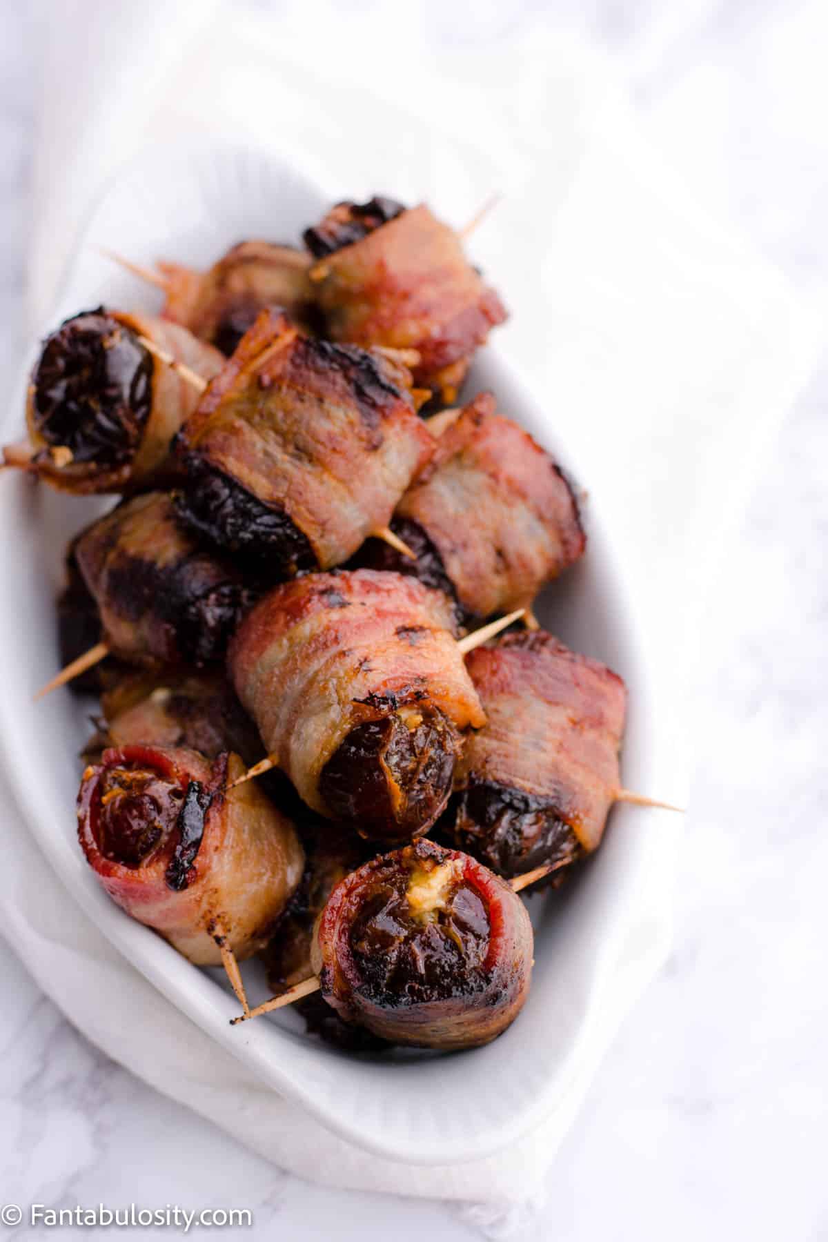 Bacon wrapped dates piled up in white dish