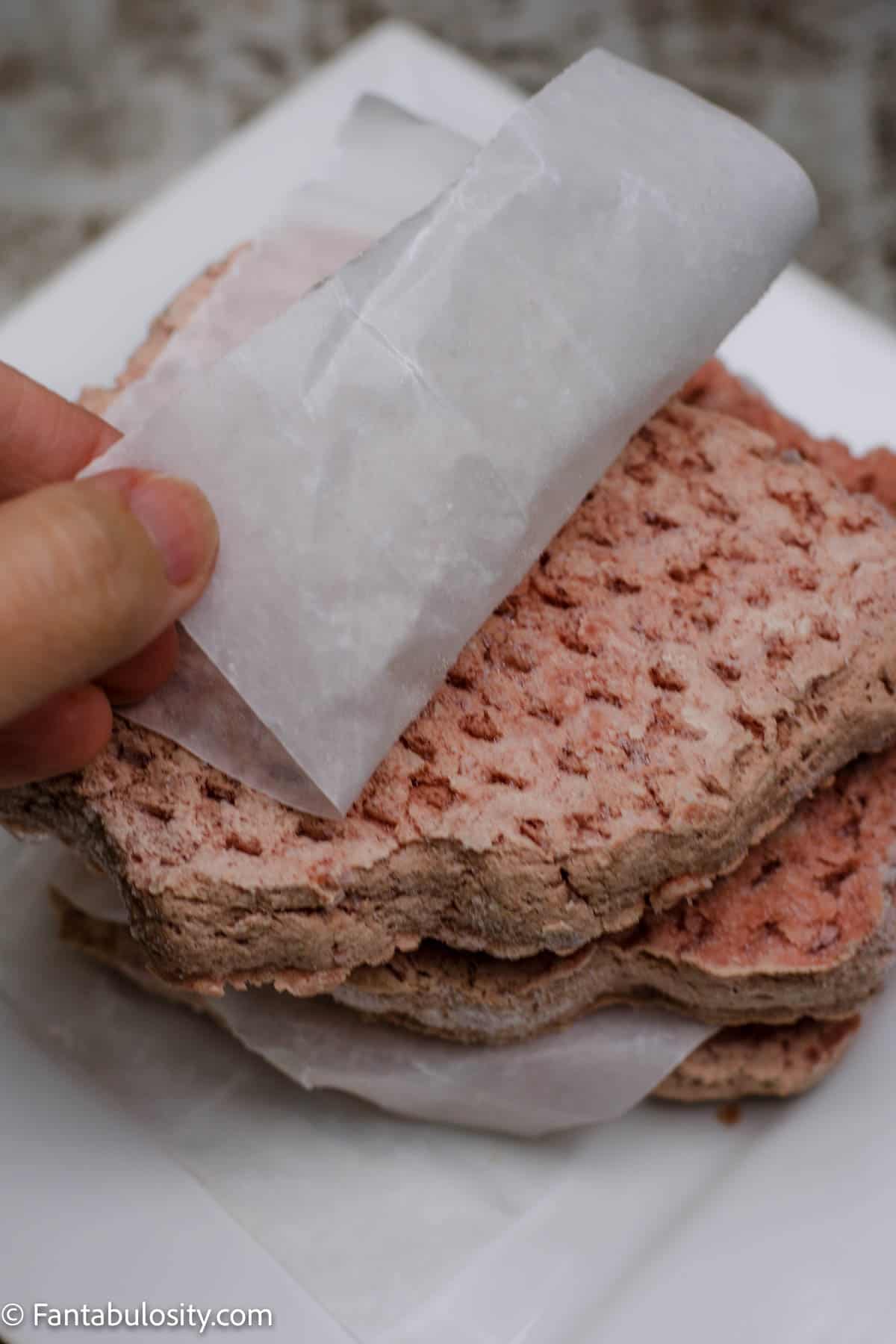 Remove the white paper from frozen burger patties