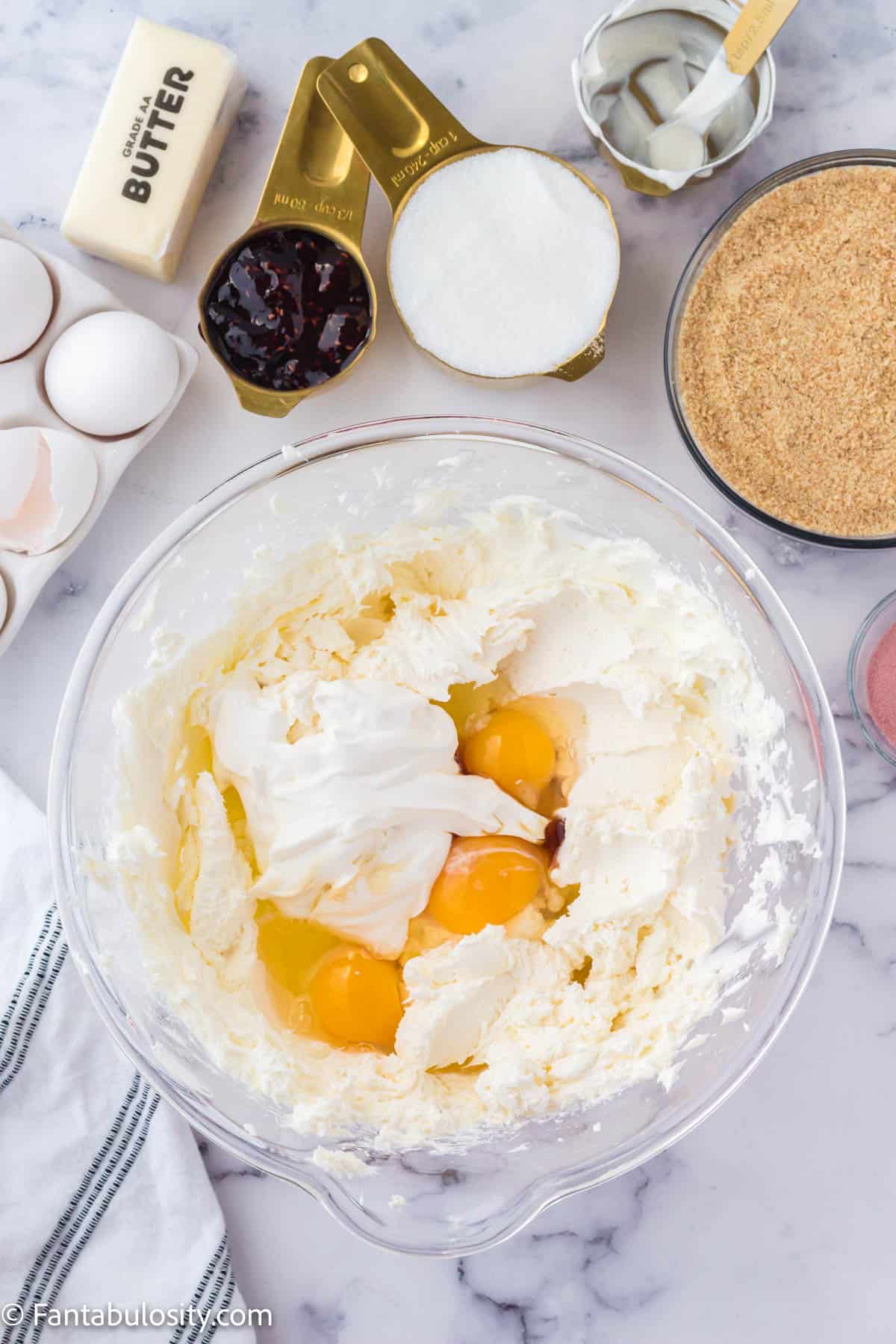 Eggs, sour cream and vanilla to cream cheese in cheesecake batter.