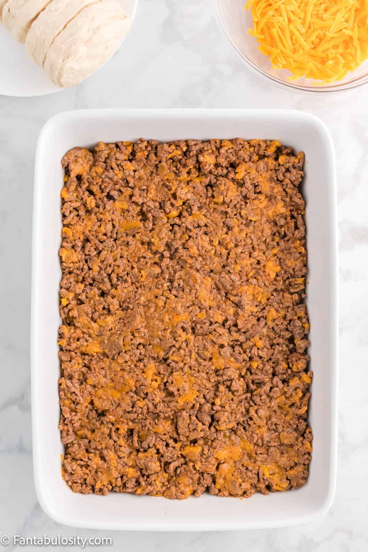 The cooked beef and cheese mixture pressed into the prepared 9x13 pan.