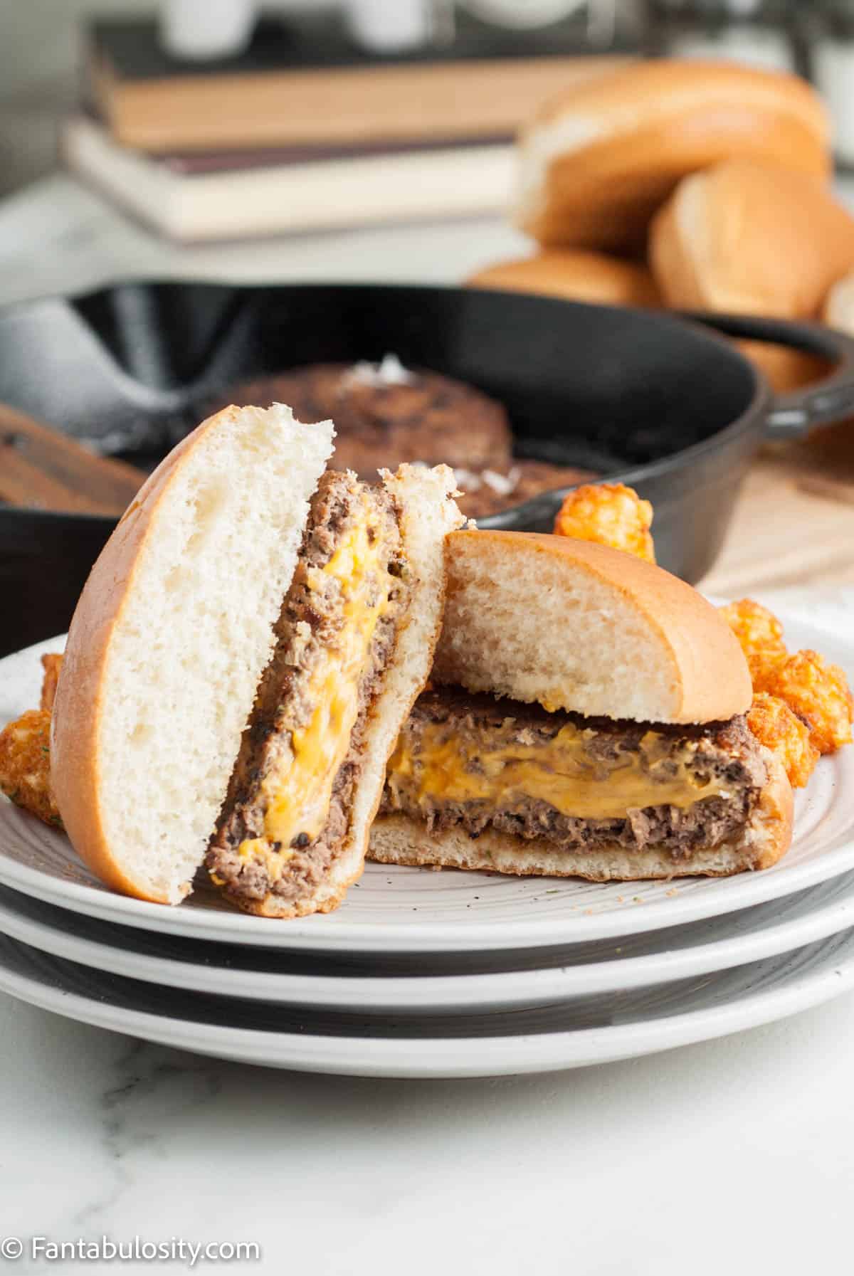 A Juicy Lucy burger on a plate cut in half to reveal the cheese inside.