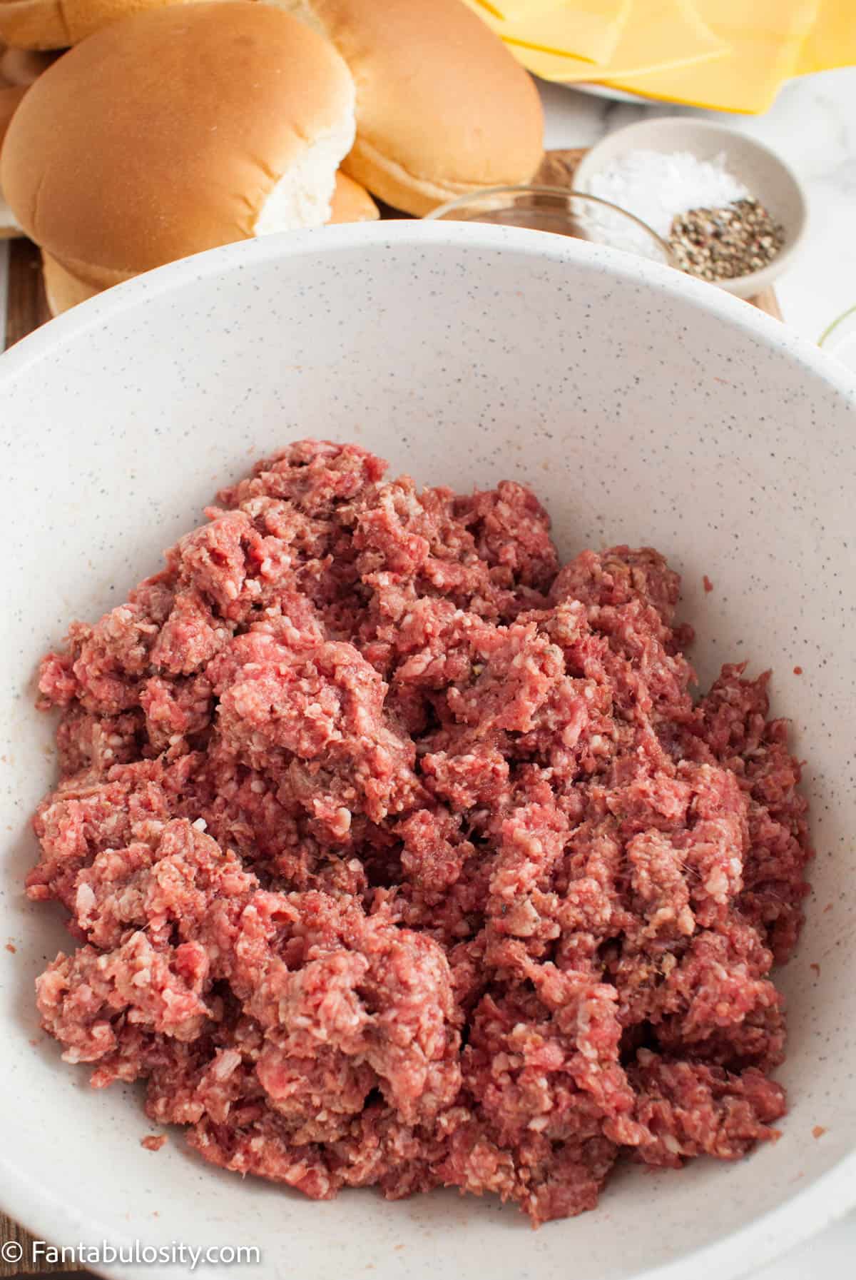 Ground beef combined with spices in a bowl. 
