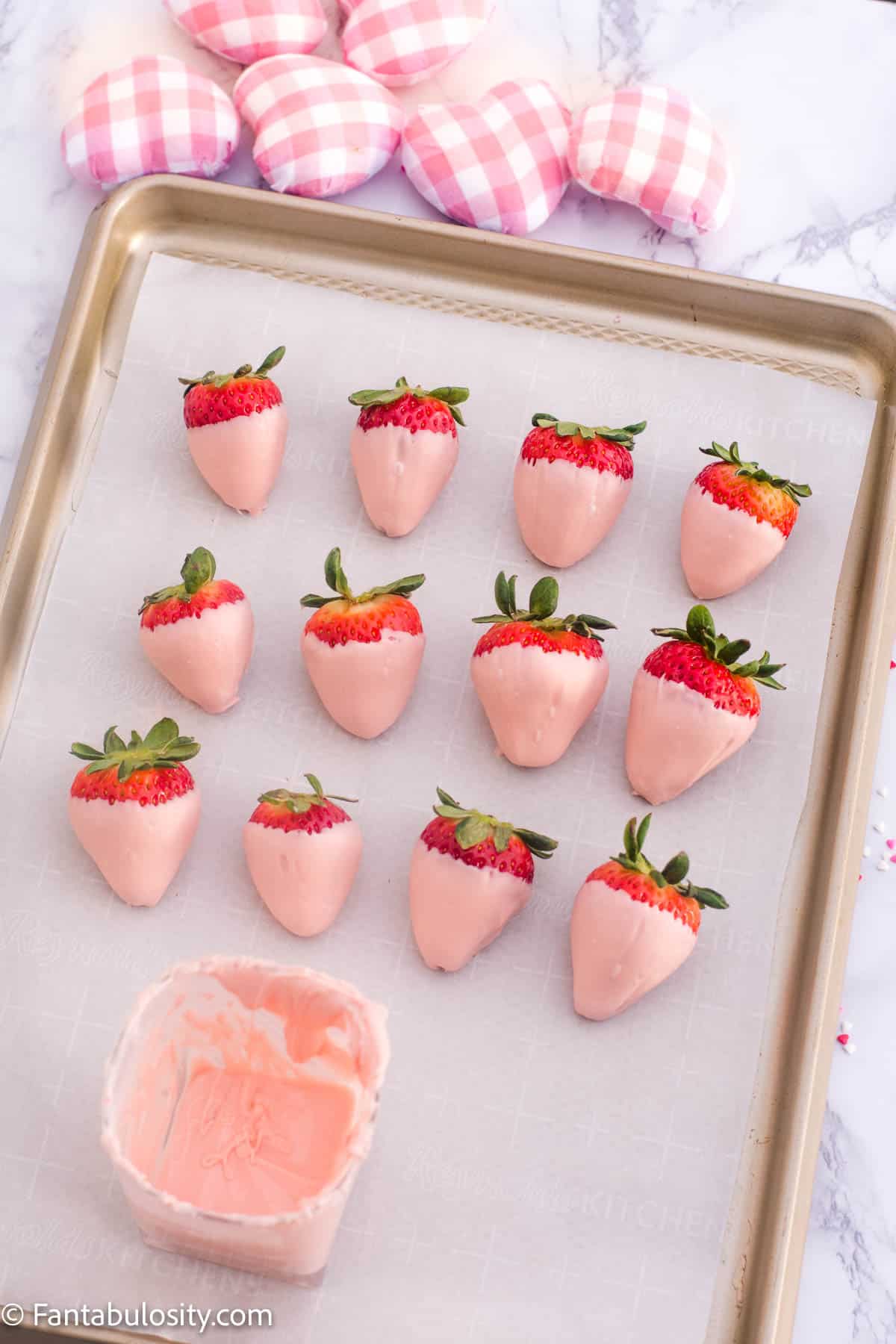 multiple pink chocolate covered strawberries on baking sheet