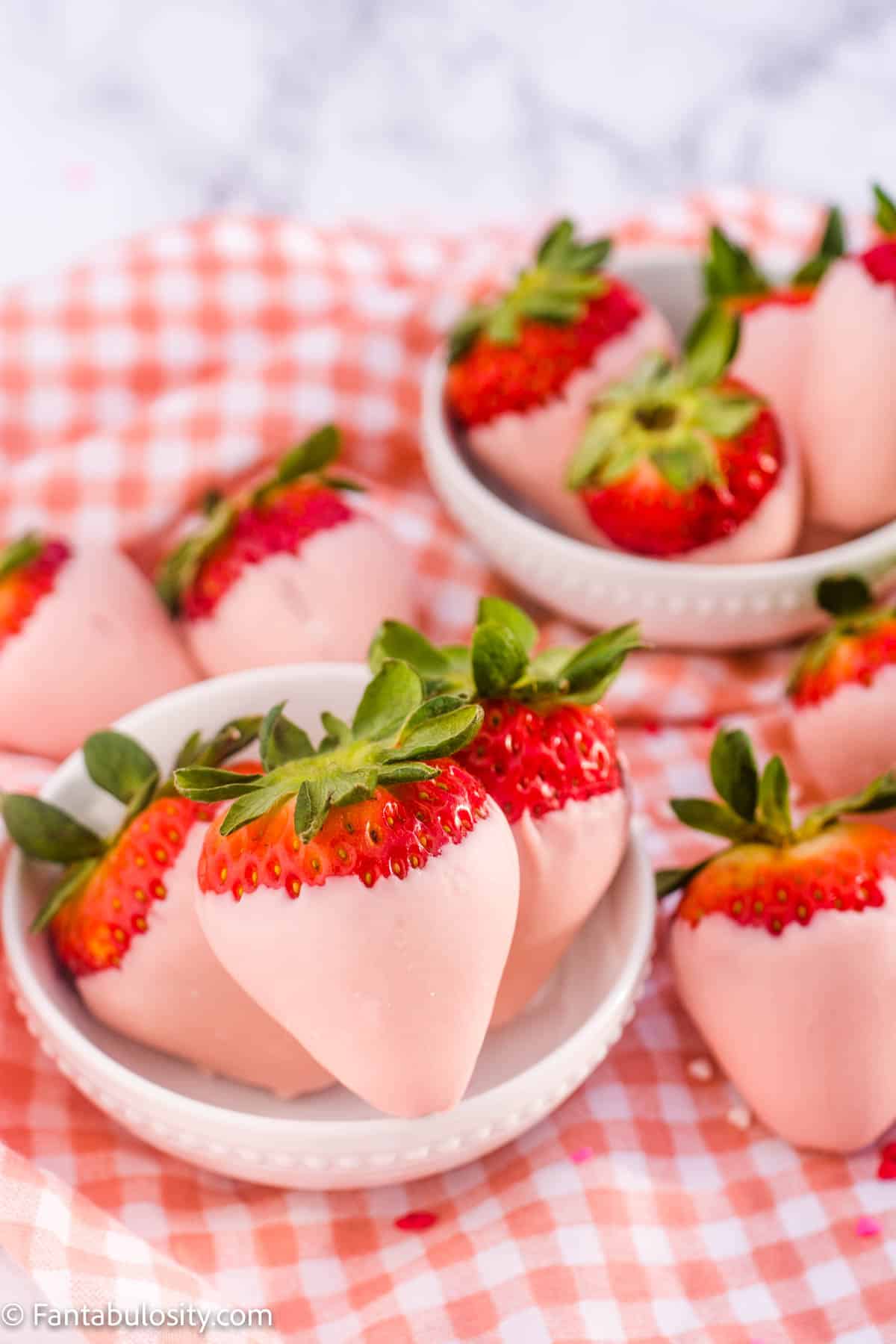Pink chocolate covered strawberries in small white bowls