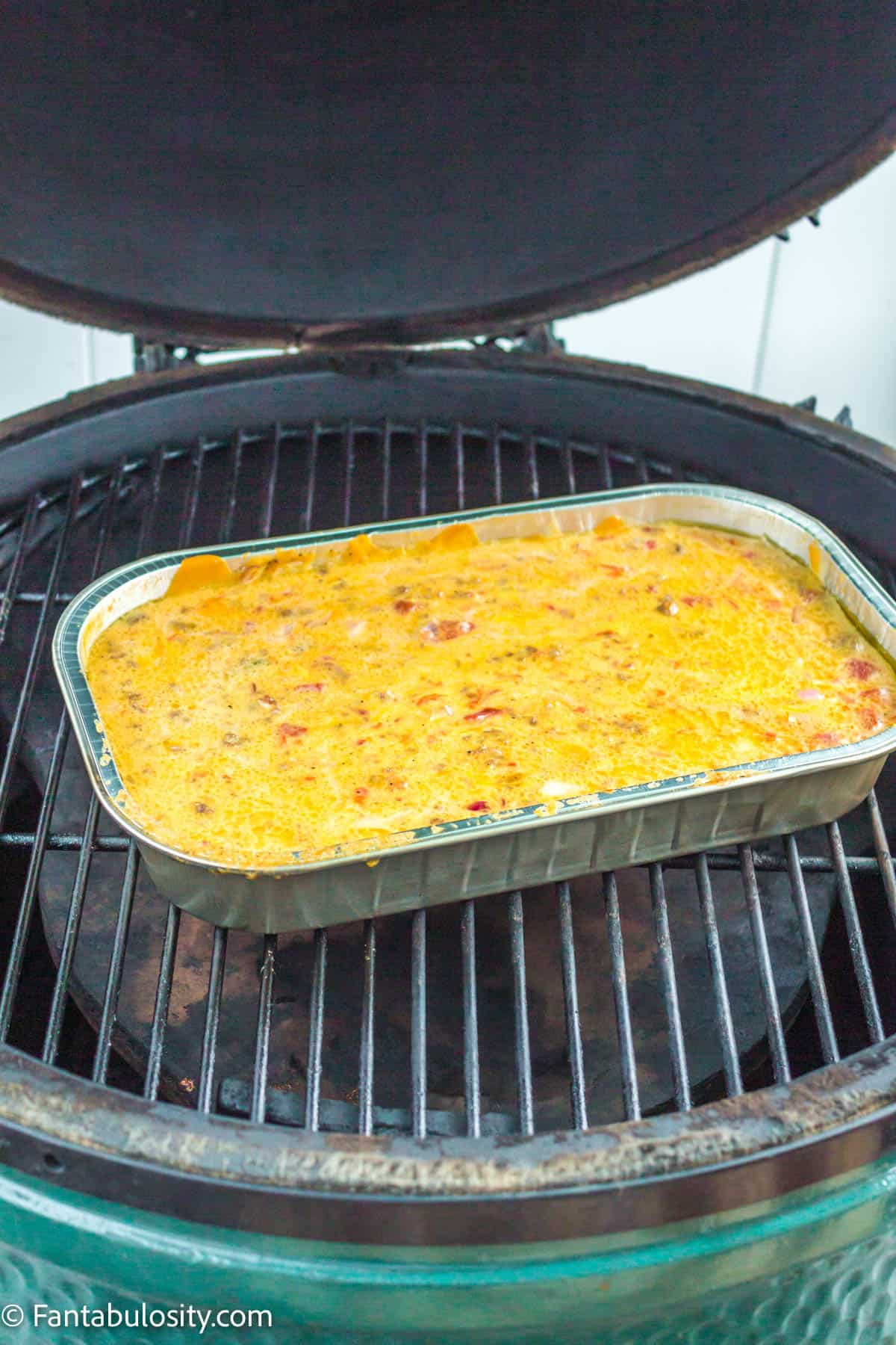 The cooked smoked queso sitting on the charcoal grill.