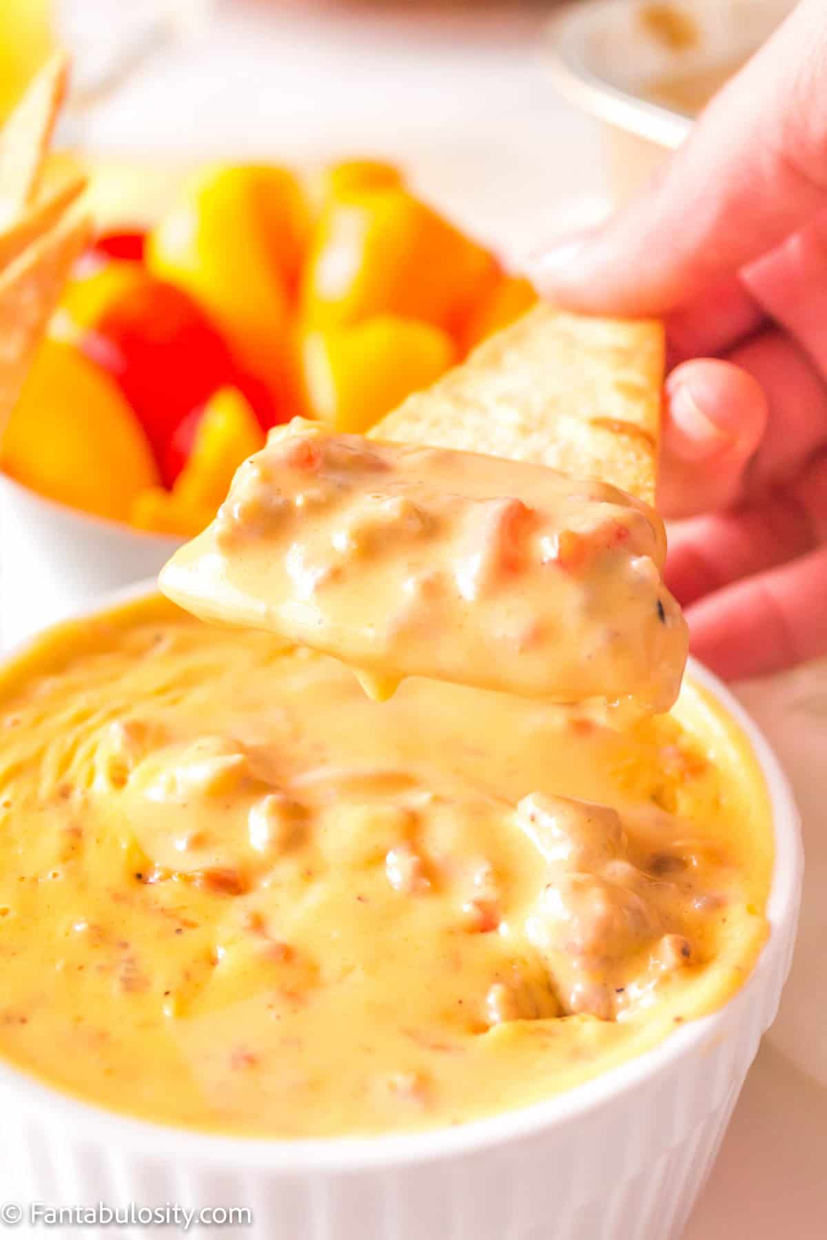 A pita chip being dipped in the smoked queso dip.