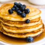 Almond milk pancakes with syrup and blueberries on them.