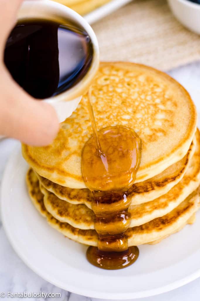 Pouring syrup over almond milk pancakes.