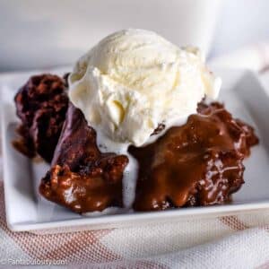 Hot fudge cake sitting on white plate, with a scoop of vanilla ice cream on top.