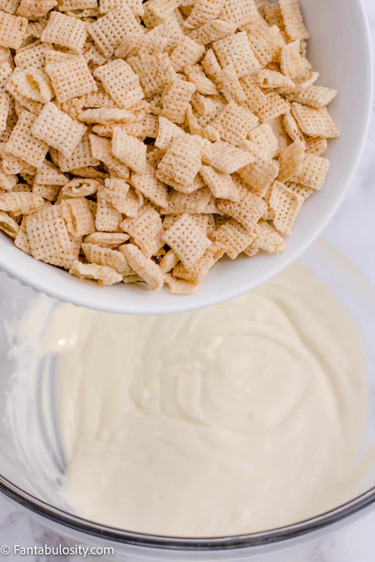 A bowl of cereal about to be poured into a bowl of melted white chocolate.