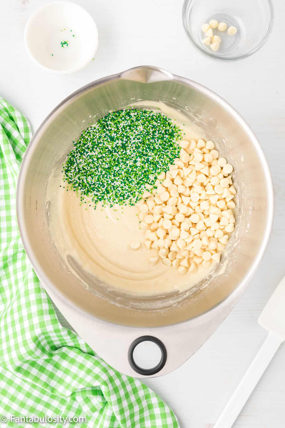Sprinkles and white chocolate chips poured into the bowl of batter. 