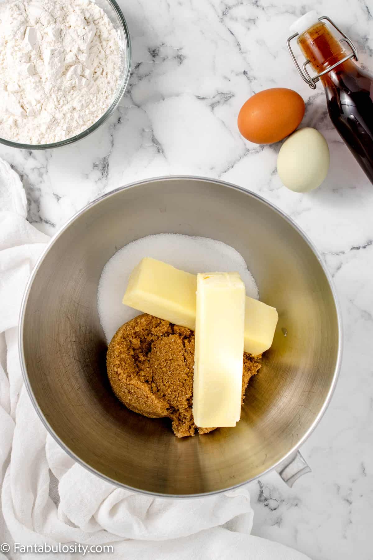 Butter, white sugar and brown sugar in a mixing bowl. 