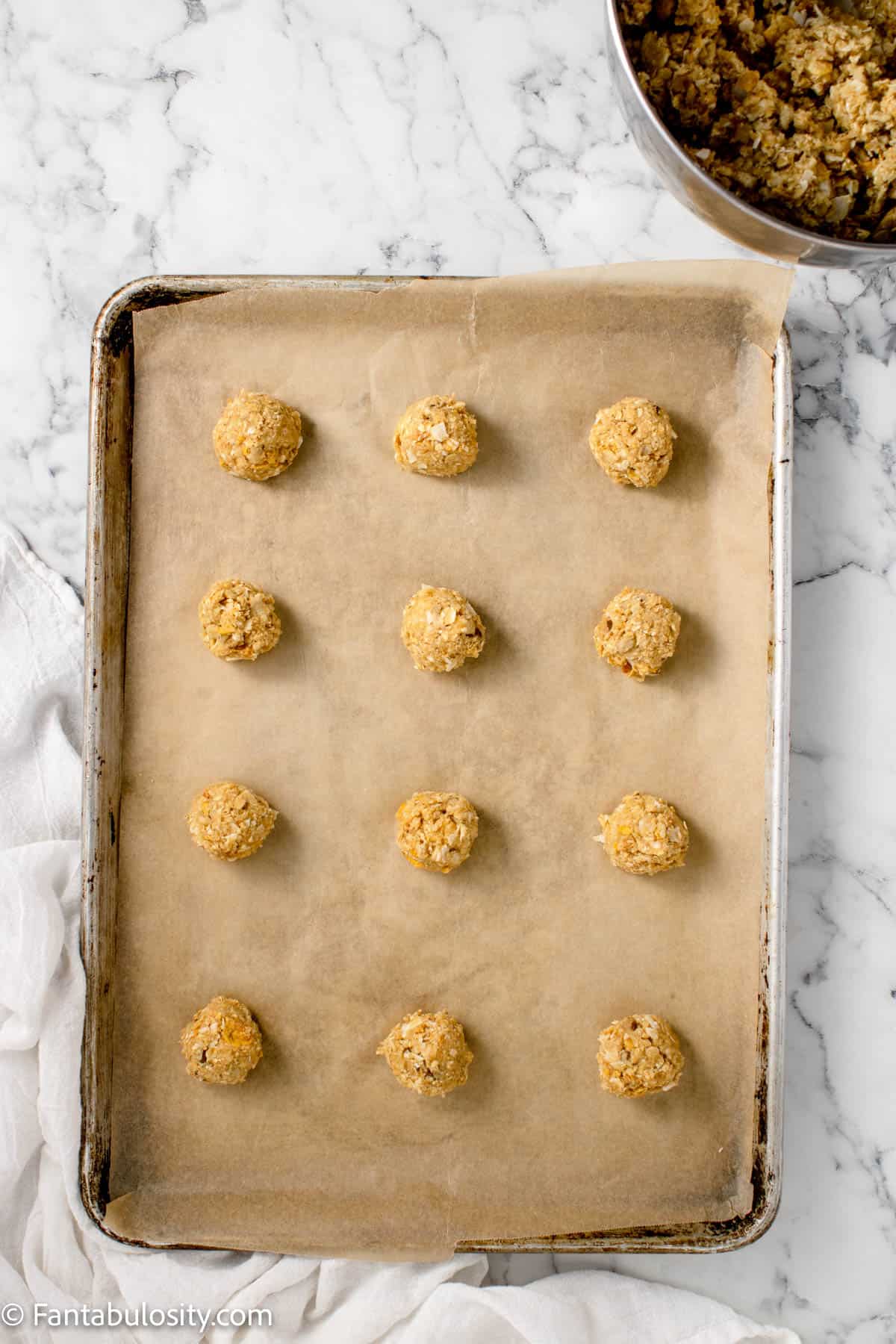 Balls of cookie dough on parchment lined baking sheet.