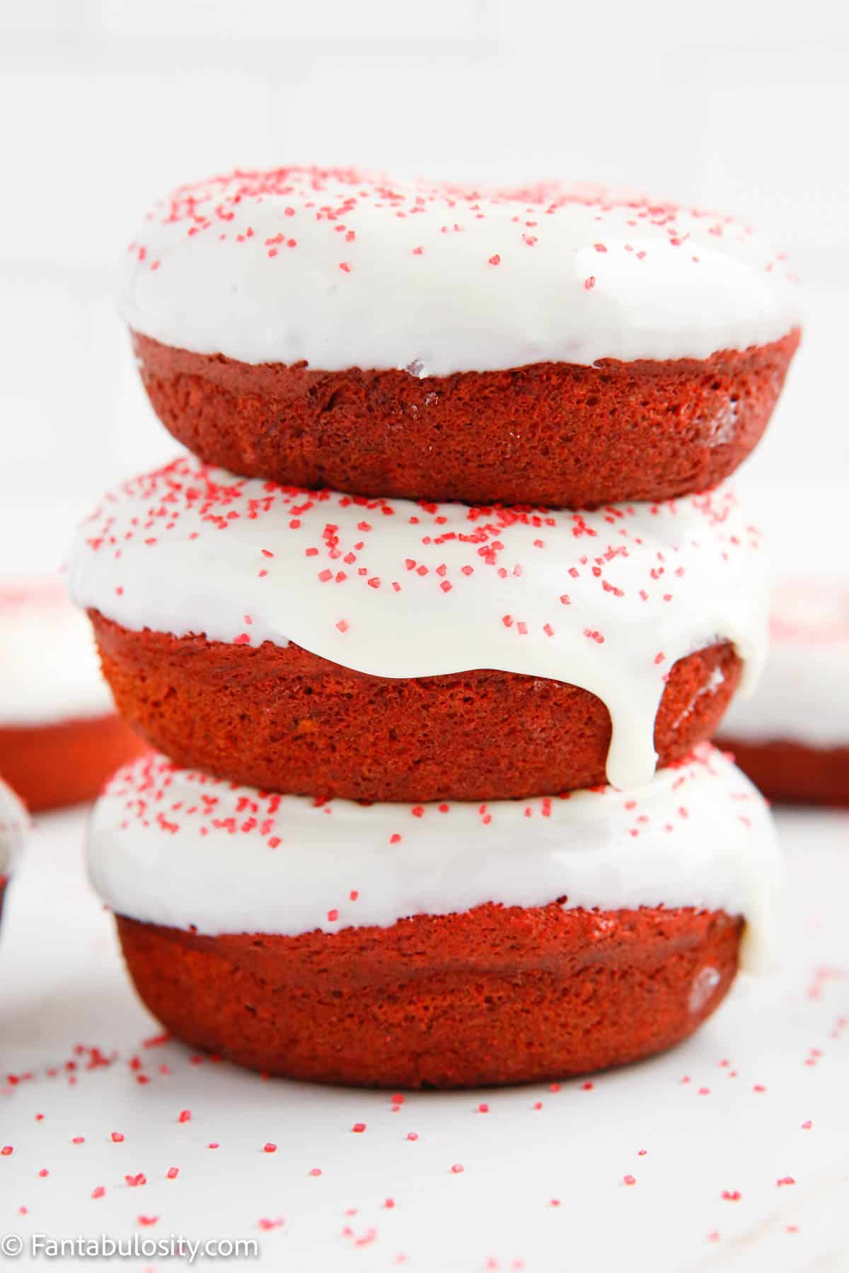 Three red velvet donuts stacked on top of each other. 
