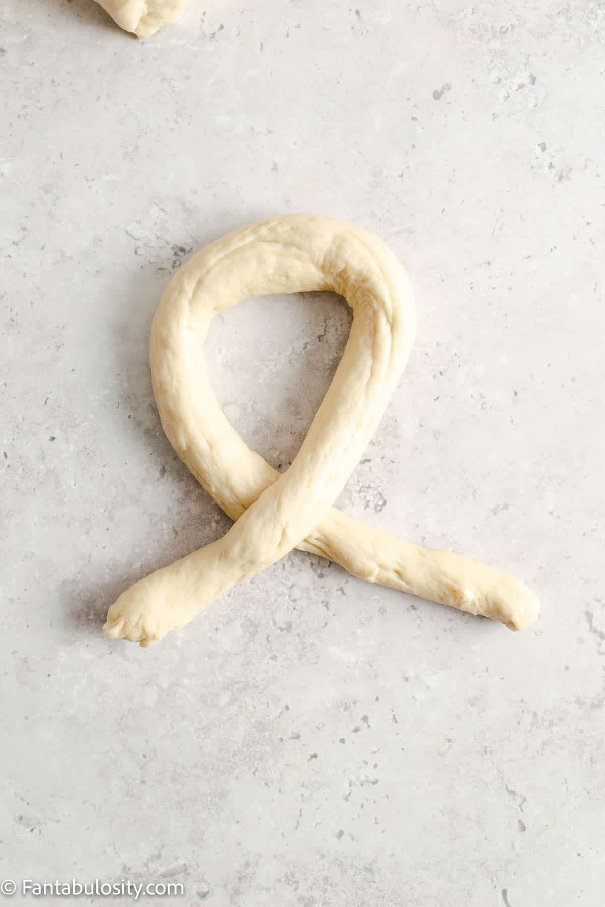 Pretzel dough with tails crossed over each other.