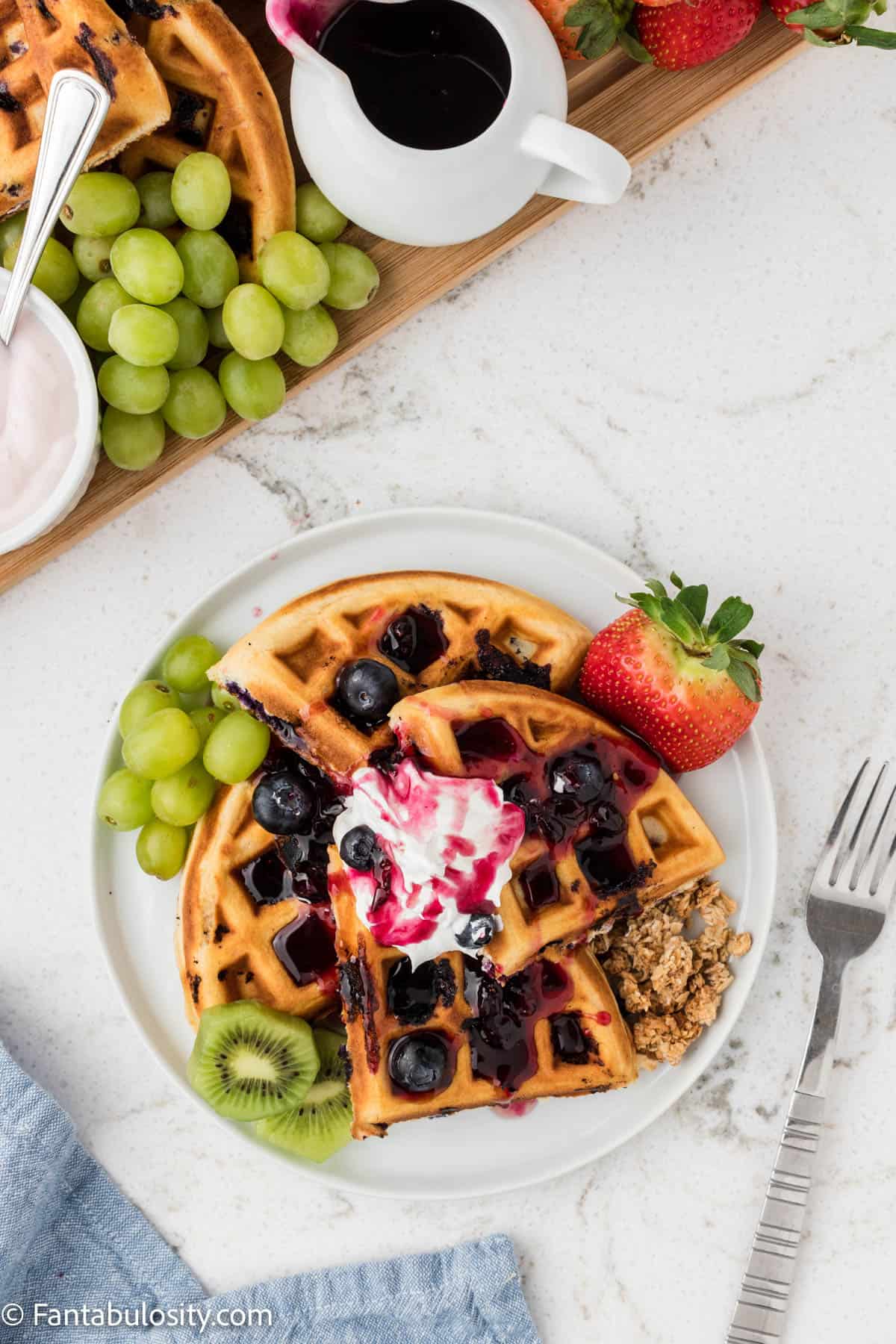 Waffles with yummy toppings and fruit on a plate.